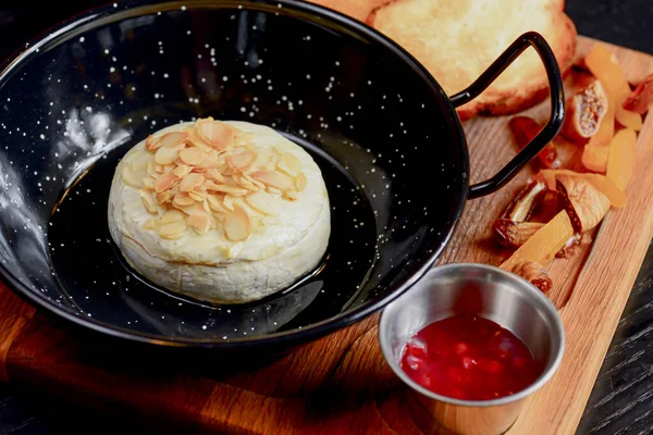 Baked Cheese - Melted cheese with bread and sauce served in a bowl on wooden rustic cutting board.