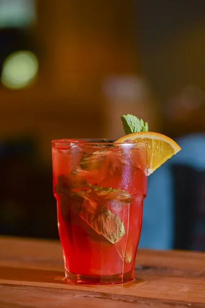 Cóctel clásico de verano alcohólico con decoración de limón y menta en una mesa de bar . — Foto de Stock