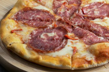 Bütün salamlı pizzayı siyah ahşap bir masanın üzerinde dilimledim. Fast food, abur cubur kavramı.