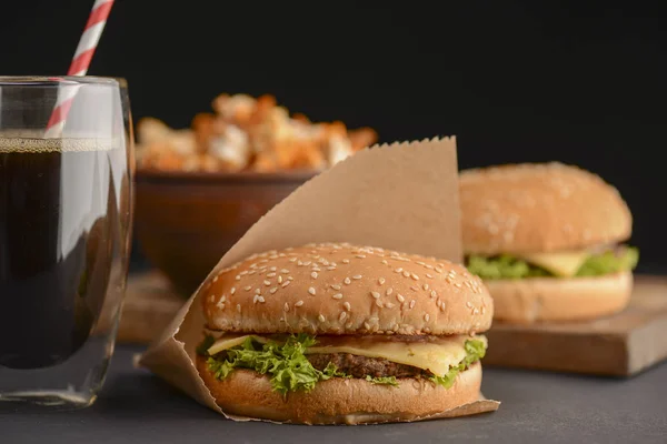 Amerikanischer Imbiss, zwei große Burger, ein Glas Cola und eine Schüssel salzigen Popcorn. Fast Food, Junk Food Konzept. — Stockfoto