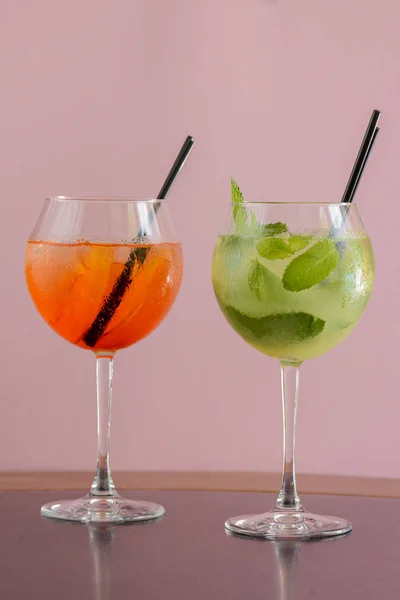 Two mojito alcohol cocktails with plastic straw, tropical beverage with ice, mint and lime on pink background copy space — ストック写真