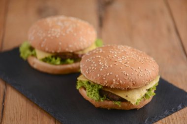 Siyah tahtadaki ahşap masada iki hamburger var. Fast food, abur cubur konsepti. Yemek fotoğrafçılığı konsepti.