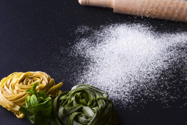 Siyah zemin üzerinde İtalyan spagettisi ve zeytinyağı şişesi ve merdane iğnesi..