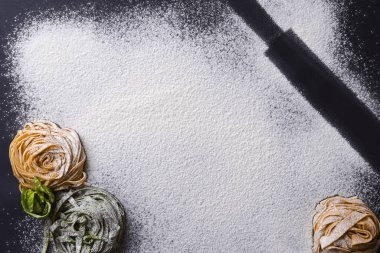 Siyah zemin üzerinde İtalyan spagettisi ve zeytinyağı şişesi ve merdane iğnesi..