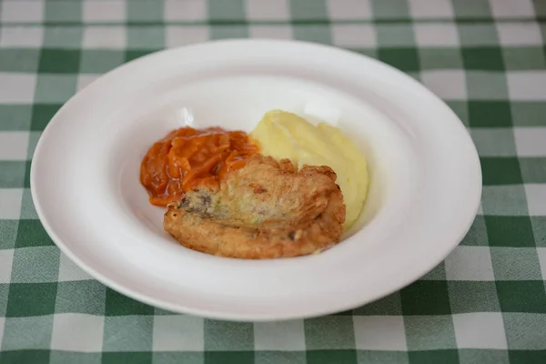 Stekt fiskfilé med potatismos och tomatsås serverad på vit tallrik på träbord. — Stockfoto