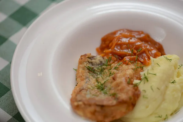 Gefrituurde visfilet met aardappelpuree en tomatensaus geserveerd op wit bord op houten tafel. — Stockfoto