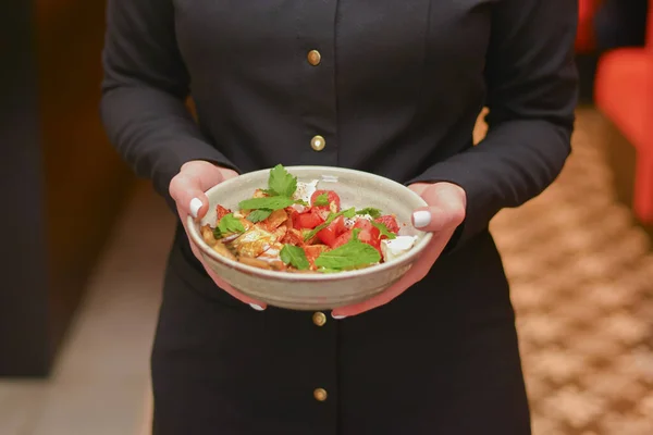 Restaurant services. Waitress with food dish serving vegetable salad in restaurant.