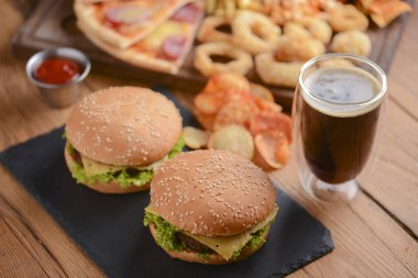 Köy ahşap masada iki hamburger, kola ve diğer fast food. Fast food, abur cubur kavramı.