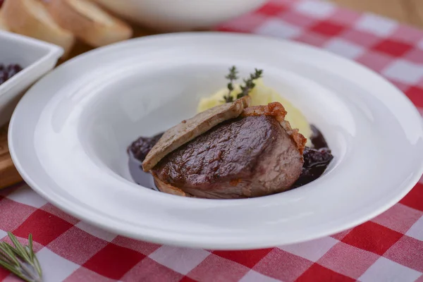 Картофельное пюре с мясом и соусом подается в белой тарелке над красной клетчатой скатертью . — стоковое фото