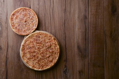 Koyu kırsal ahşap masada iki pizza. Düz yerde, üst tarafta. Uzay web tasarım afişini kopyala.