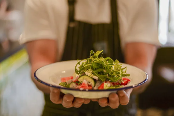 Waiter holding fresh vegetable organic salad, ready to serve. Vegan healthy diet, vegetarian food.