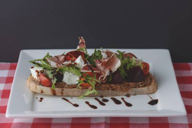 Kızarmış domatesli İtalyan aperatif bruschetta, mozzarella peyniri, sarımsak, otlar, prosciutto crudo ve sos..