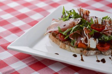 Kızarmış domatesli İtalyan aperatif bruschetta, mozzarella peyniri, sarımsak, otlar, prosciutto crudo ve sos..