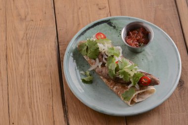 Et sosisleri taze yeşillik ve lahanalı ekmek ile sos tavasında ahşap bir tabakta servis edilir..