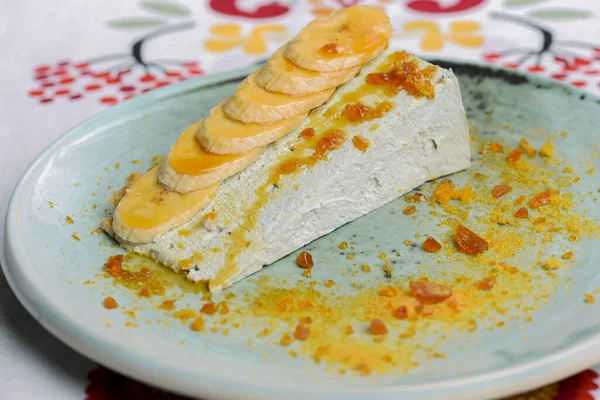 Ein Stück Sahnetorte mit Bananen auf einem blauen Teller serviert. Süßes zuckersüßes Sahnedessert. Obstkuchenkuchen. — Stockfoto