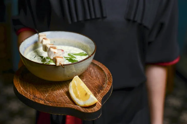 Garson bir restoranda Okroshka servis ediyor. Yaz aylarında soğuk yoğurt çorbası, salatalık, turp, yumurta ve dereotlu. — Stok fotoğraf