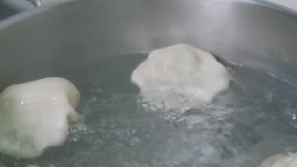 Грузинская кухня. Хинкали или пельмени кипят в кипяченой воде на плите в кастрюле. Процесс приготовления пищи вблизи — стоковое видео
