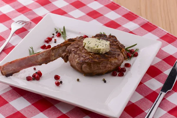 Rack van lam geserveerd met granaatappel zaden en saus op witte plaat over rode ruitvormige tafelkleed. Italiaans concept. — Stockfoto