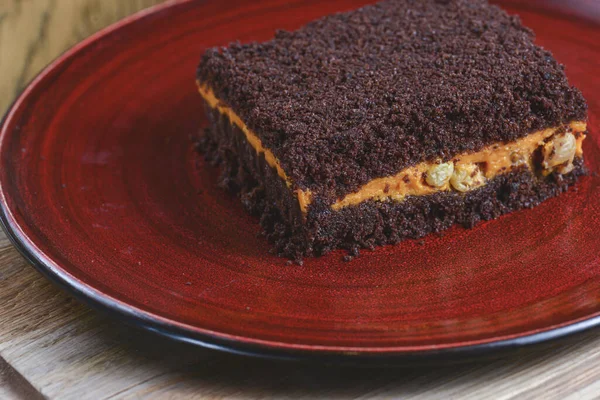 Homemade carrot cake with pumpkin, a piece of brownie cake served on red plate over dark rustic wooden background. — Stock Photo, Image