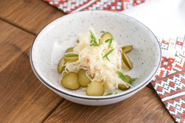 Lahana turşusu. Ekşi lahana salatası, beyaz kâsede koyu kırsal ahşap masa arkasında servis edilir..