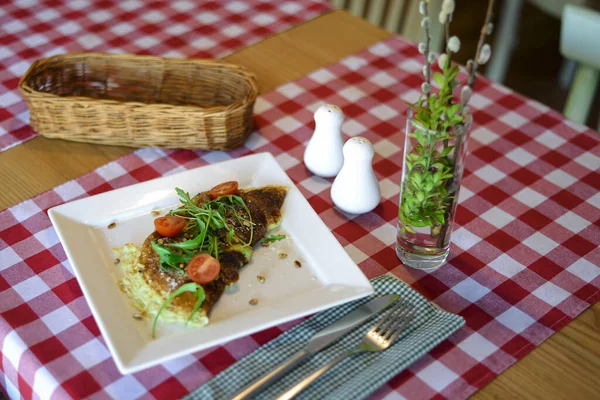 Tortilla con verduras servida en un plato blanco cuadrado sobre fondo de mantel a cuadros rojos con cubiertos . — Foto de Stock