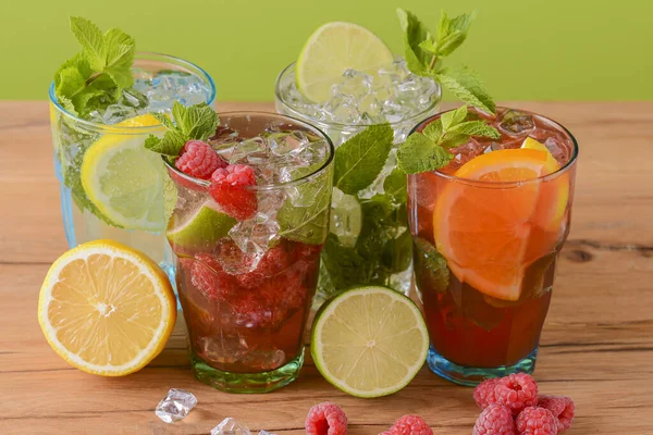 Four tropical mixed drinks, orange, lemon and raspberries cocktails over bright pastel green background. — Stock Photo, Image