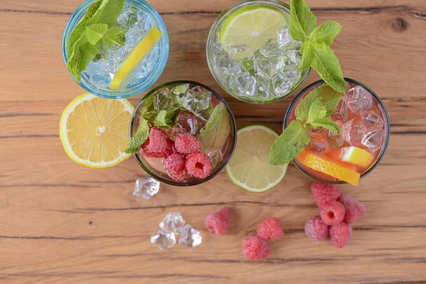 Cztery tropikalne napoje mieszane, koktajle pomarańczowe, cytrynowe i malinowe podawane na jasnodrewnianym stole. — Zdjęcie stockowe