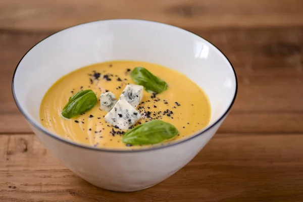 Kremalı balkabağı çorbası beyaz bir kâse içinde ahşap bir masada peynir. Restoran fotoğrafçılığı konsepti. — Stok fotoğraf