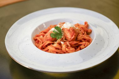 Bolonez soslu makarna ve siyah ahşap masada beyaz tabakta parmesan peyniri..