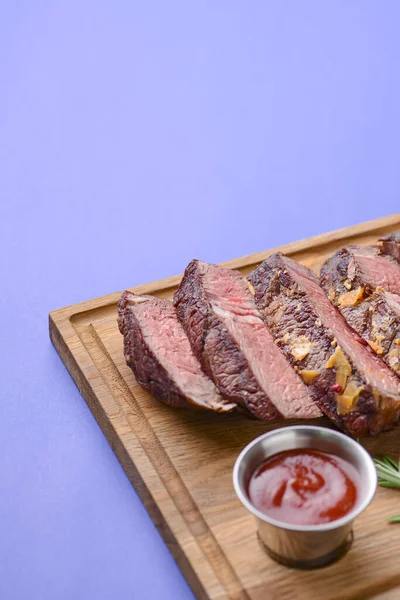 Sliced grilled Medium rare barbecue Steak on bone with spices served on a rustic wooden board over blue background.