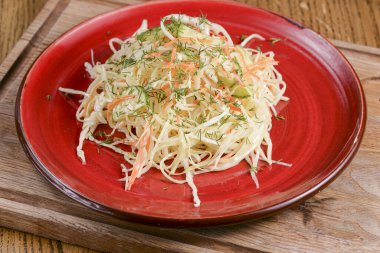 Lahana turşusu. Kırmızı tabakta servis edilen ekşi lahana salatası koyu kırsal ahşap masa arka planında