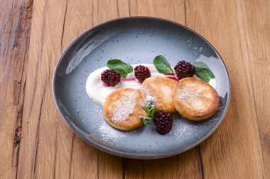 Koyu kırsal ahşap arka planda servis edilen bir tabakta soslu tatlı patates krepleri. Kopyalama alanı olan pankart.