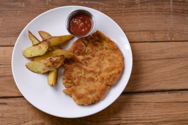 Sulu biftek, domates sosu ve patates kızartması. Koyu kırsal masa üzerinde beyaz tabakta servis ediliyor..