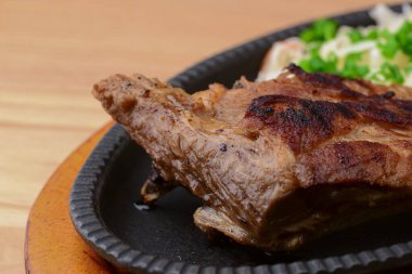 Sebzeli ızgara biftek ve ekşi lahana salatası siyah bir tabakta servis edilir..