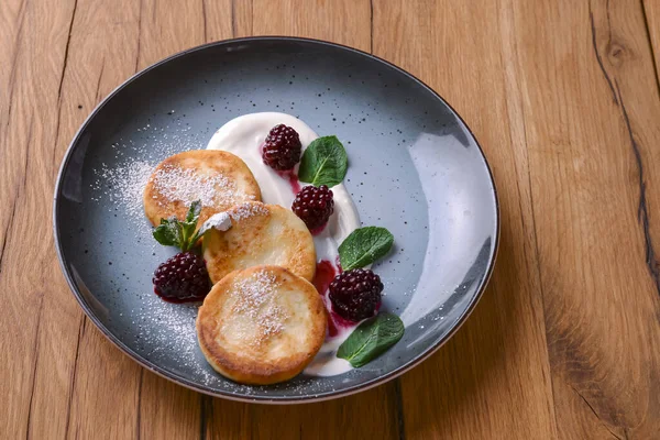 Koyu kırsal ahşap arka planda servis edilen bir tabakta soslu tatlı peynirli krep. Kopyalama alanı olan pankart.