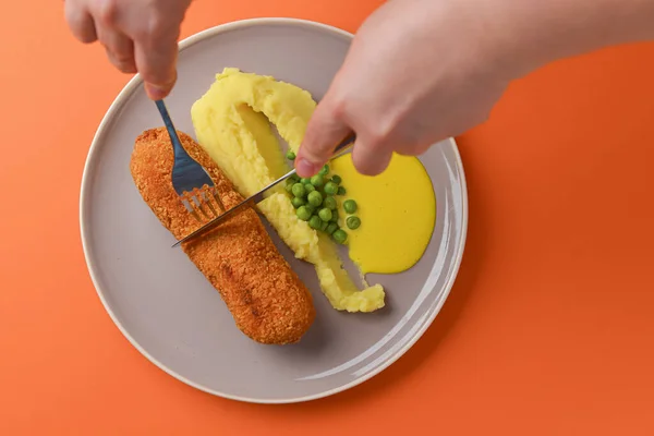 Cordon bleu cutlet, friterat kött serveras med potatismos och gröna ärtor på grå platta över orange bakgrund. — Stockfoto