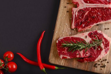 Taze çiğ biftek, ahşap kesim tahtası, siyah arka plan, baharatlar, üst manzara..
