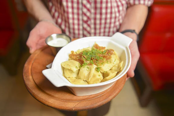 Garson bir tabak lezzetli İtalyan yemeği hazırlıyor Ravioli. Restoranda İtalyan mutfağı, et ve soslu Ravioli köftesi.