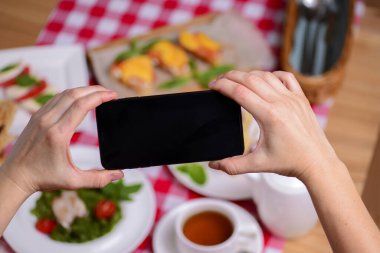 Kadın cep telefonunu farklı geleneksel İtalyan yemekleri ve tatlıları üzerinde tutuyor..