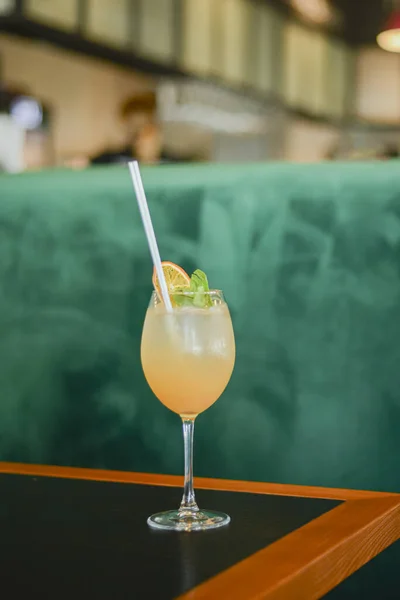 Cocktail freddo estivo con ghiaccio e arancia in un bicchiere alto su un tavolo di legno su sfondo sfocato del ristorante . — Foto Stock