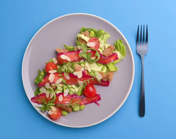 Fresh salad with smoked salted salmon, tomatoes and pumpkin seeds. Served on a gray plate over gray texture background. — Stock Photo, Image