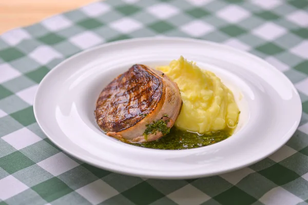 Filet mignon met aardappelpuree en pestosaus geserveerd in een wit bord over groen geruit tafelkleed. Rundsteak. — Stockfoto