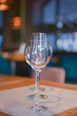 Bulanık restoranın arka planındaki ahşap masada şeffaf boş şampanya ve şarap bardakları..