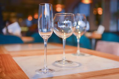Bulanık restoranın arka planındaki ahşap masada şeffaf boş şampanya ve şarap bardakları..