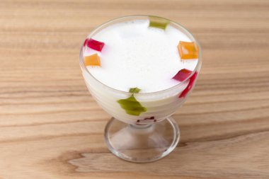 Süt ve meyve jölesi açık ahşap masada servis edilen bir bardakta. Geleneksel tatlı.