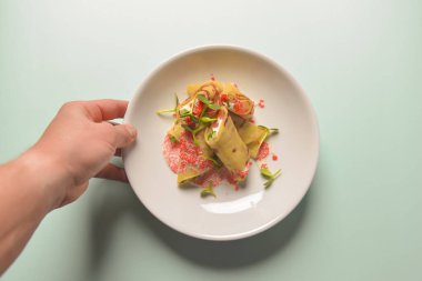 Krem peynirle doldurulmuş krepler ve ekşi soslu somon balığı ve pastel mavisi arkaplanda kırmızı havyar..