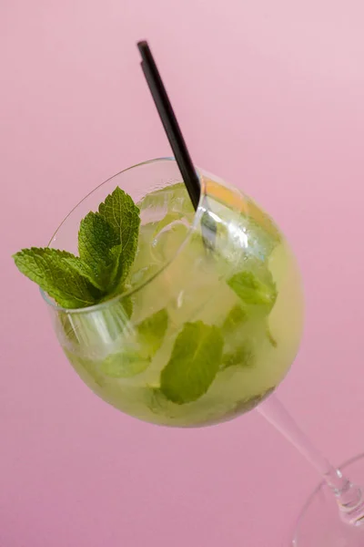 Mojito alcohol cocktail with plastic straw, tropical beverage with ice, mint and lime on pink background, copy space. — ストック写真