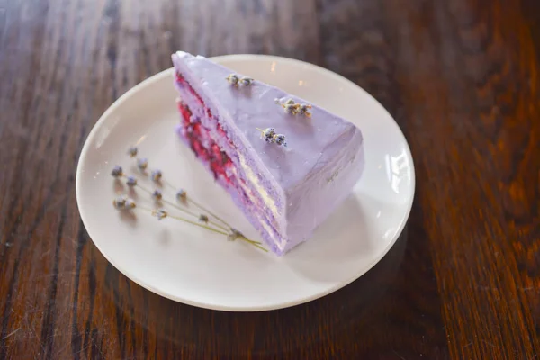 Slice of purple lavender cake with berries served with lavender flowers on a white plate. — Stock Photo, Image