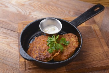 Ekşi kremalı patatesli gözlemeler ahşap bir tavada, açık sade ahşap masanın üzerinde servis ediliyor..