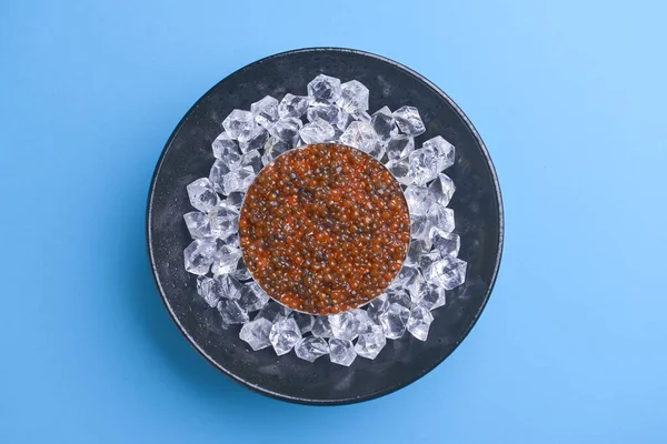 Cuenco de caviar rojo en bandeja de metal negro vintage con hielo sobre fondo azul brillante. Vista superior, espacio para copiar, plano . — Foto de Stock